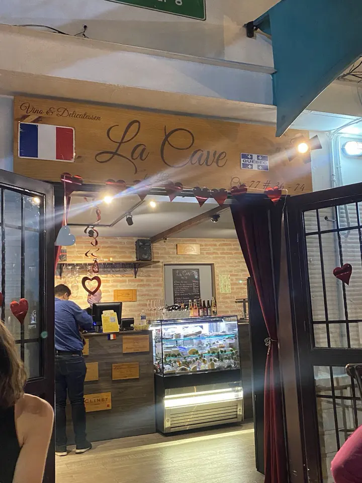 Fachada de La Cave con la bandera de Francia, el aviso y la vitrina de quesos