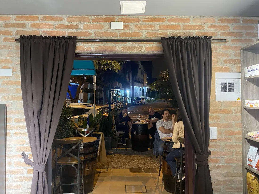 Entrada de La Cave con cortinas, paredes de ladrillo y la terraza iluminada al fondo