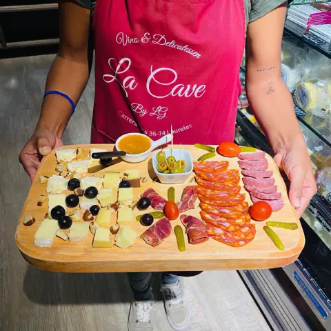 Tabla de quesos y charcutería servida con el delantal de La Cave