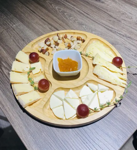 Tabla redonda de quesos con uvas y mermelada