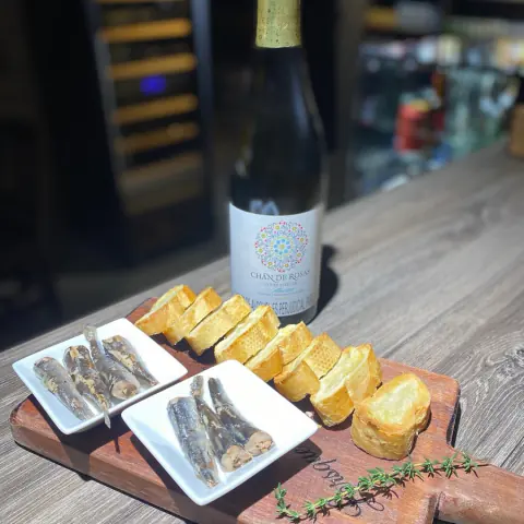 Botella de vino blanco con sardinas y tostadas